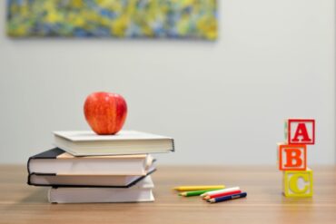 books, pencils and an apple